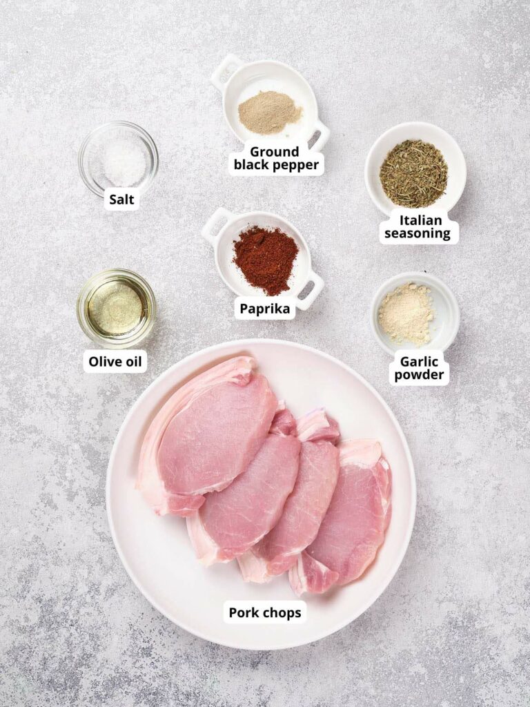 Ingredients for air fryer boneless pork chop arranged around on a speckled surface.