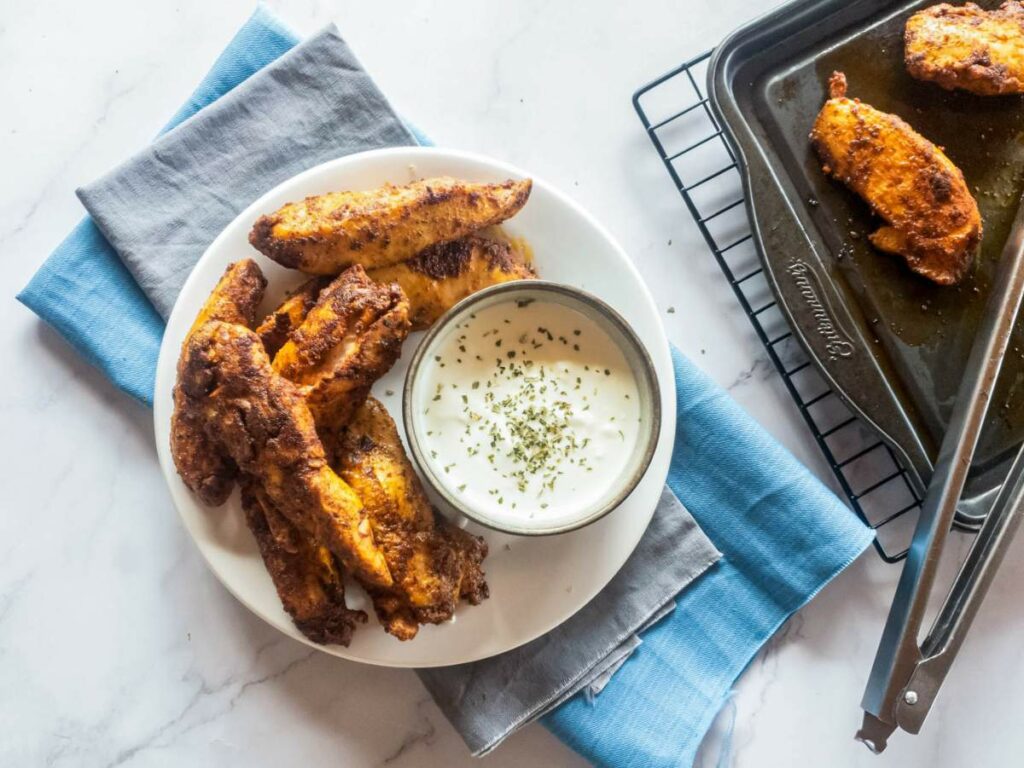 Plate of blackened chicken tenders with a bowl of dipping sauce.