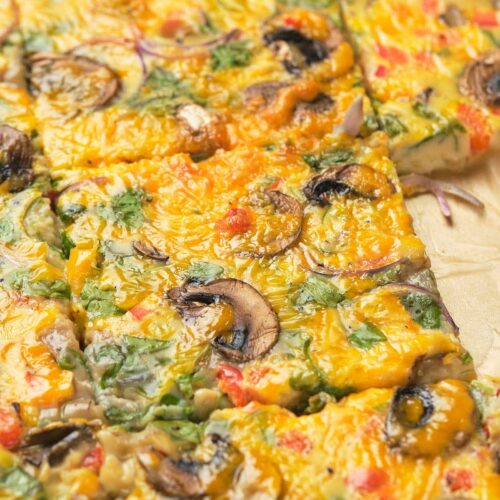 Close-up of a freshly baked sheet pan omelet with mushrooms, herbs, and melted cheese on top.