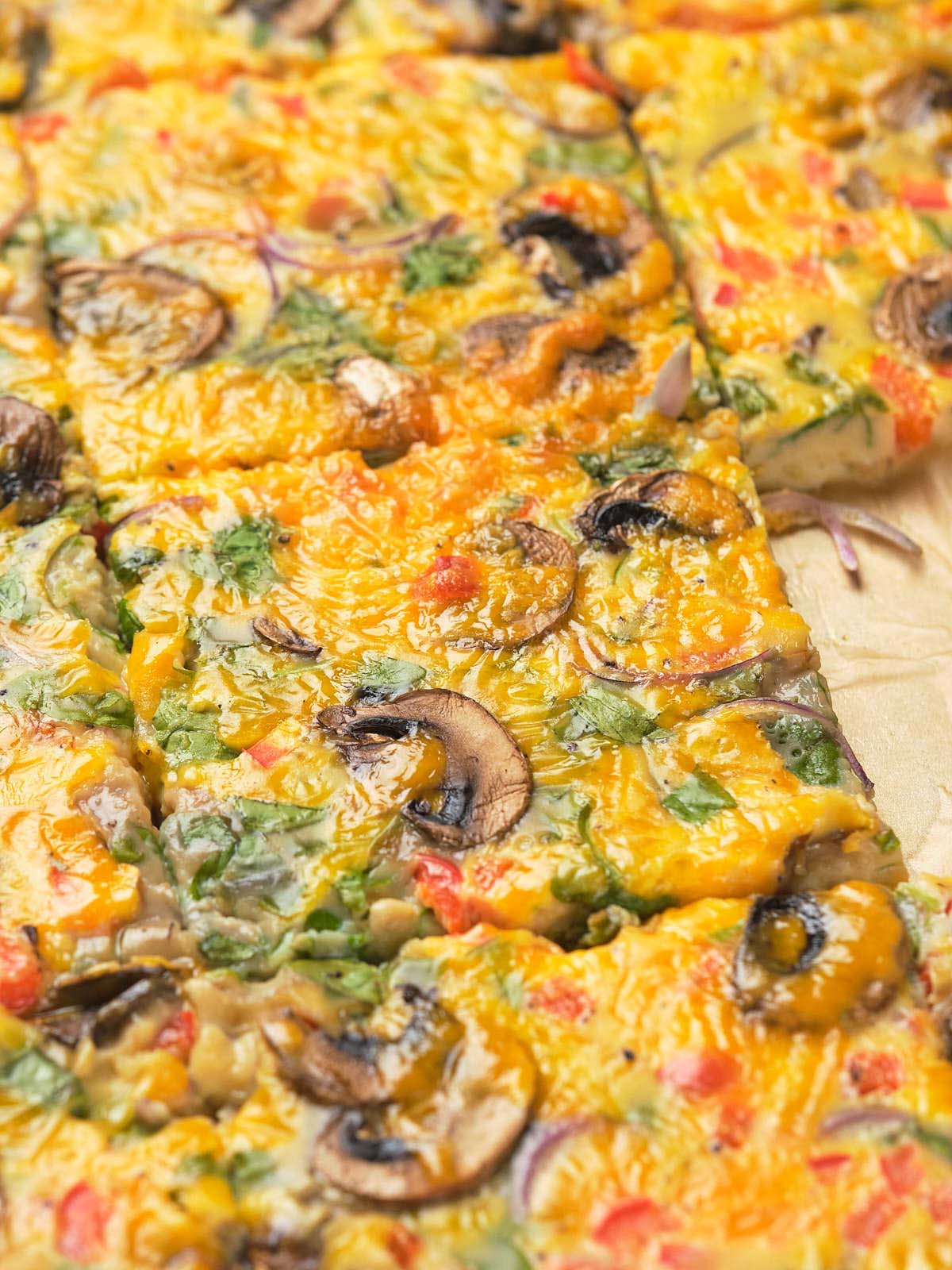 Close-up of a freshly baked sheet pan omelet with mushrooms, herbs, and melted cheese on top.