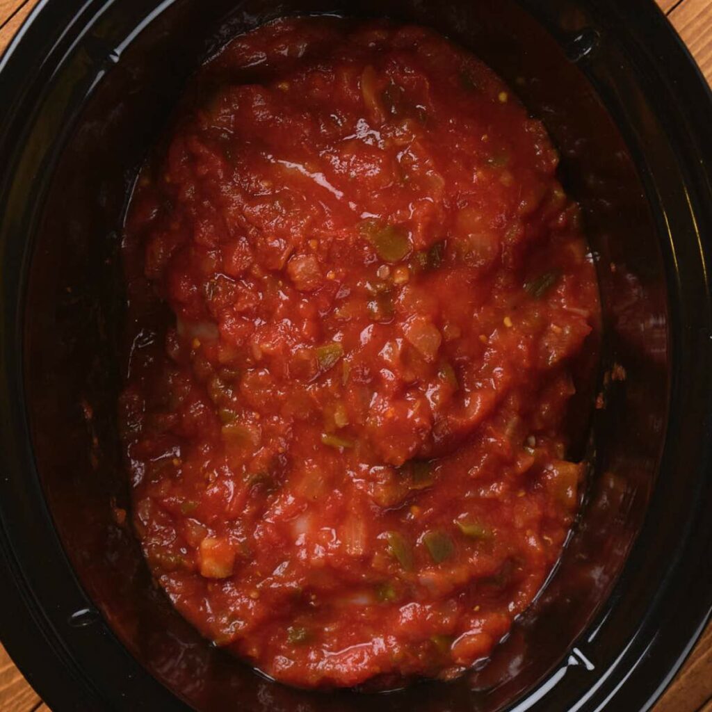 Tomato-based sauce with chopped vegetables in a black container.