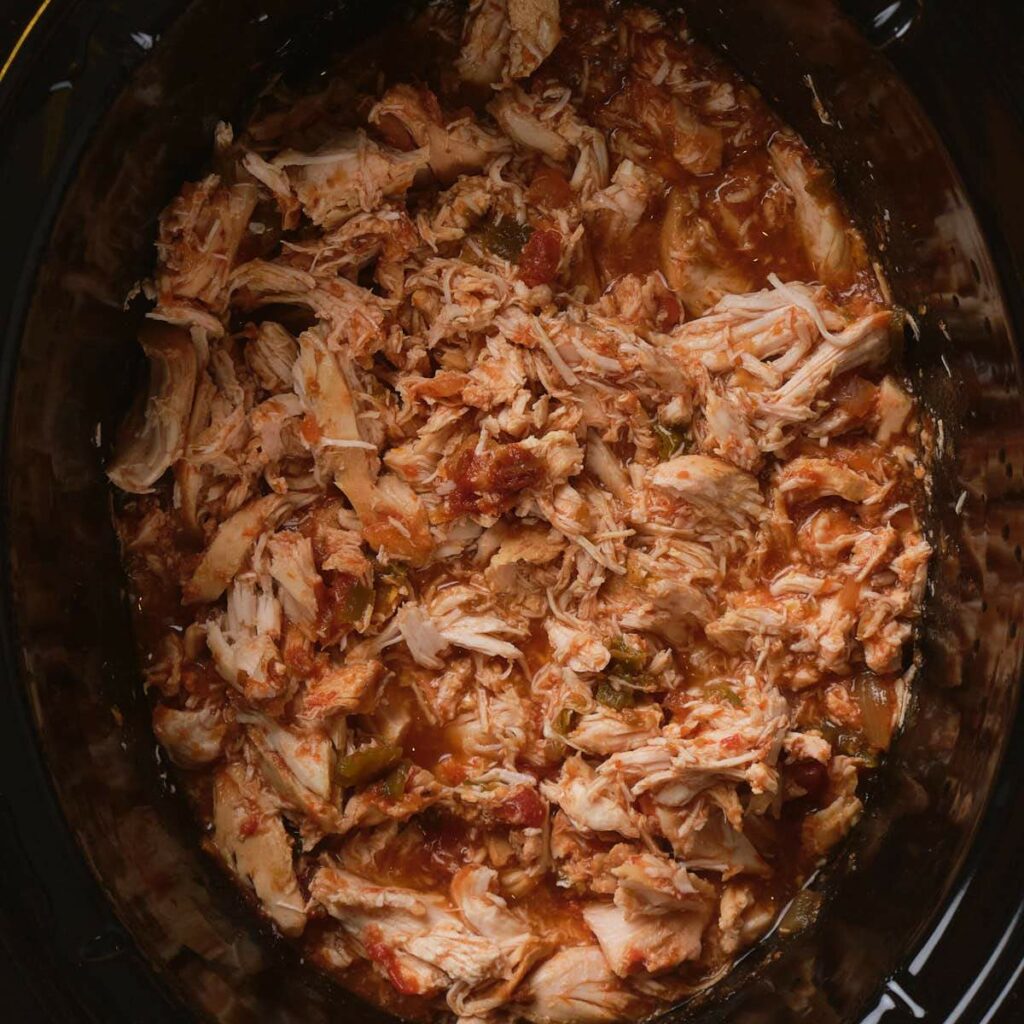 Shredded chicken in salsa sauce cooked inside a slow cooker.