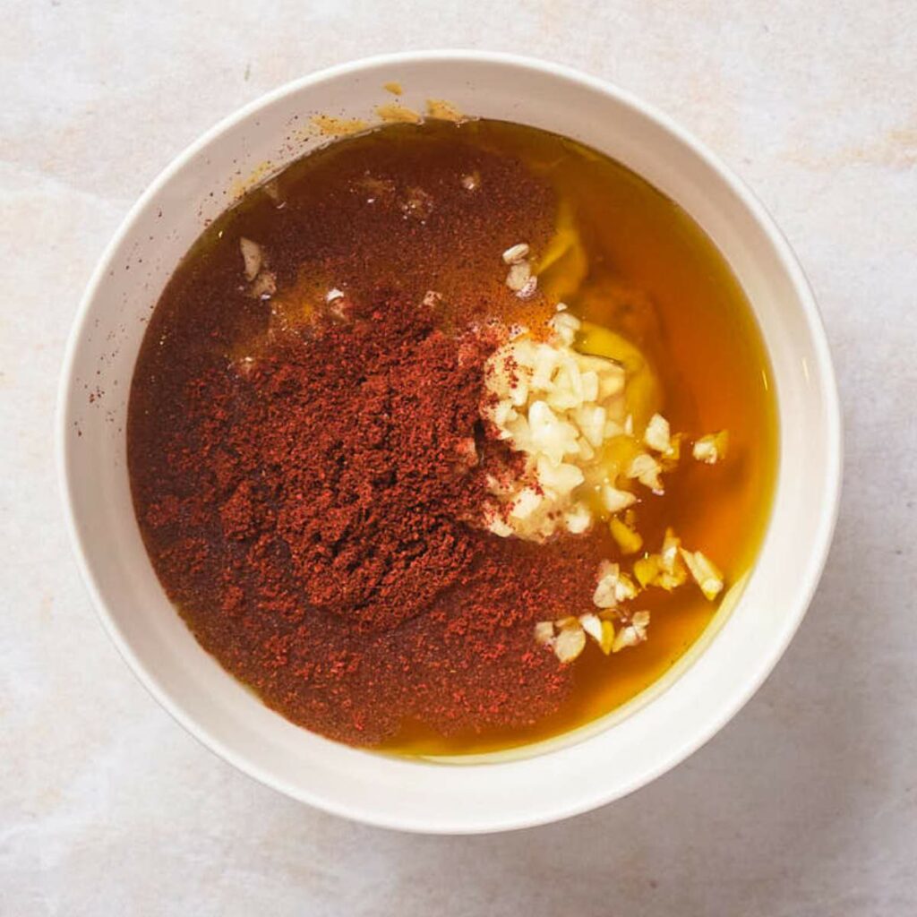 Bowl with oil, minced garlic, and red chili powder.