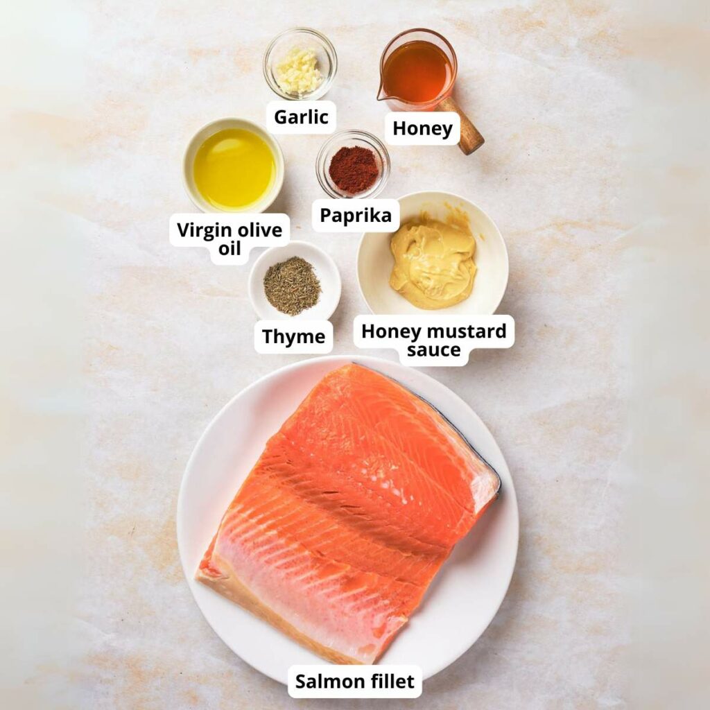 Ingredients for honey mustard glazed salmon on a surface, each labeled.